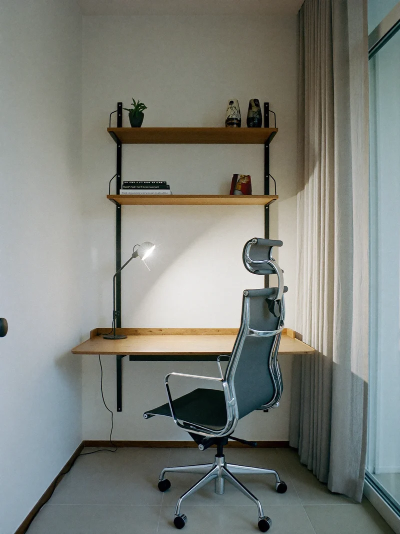 Kompakt hjemmekontor med egeskrivebord, vægreoler og arbejdslampe ved vindue